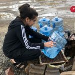 Young woman filling water jugs from clean drinking water well
