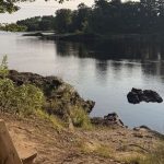 Bench by a river with rocks and trees