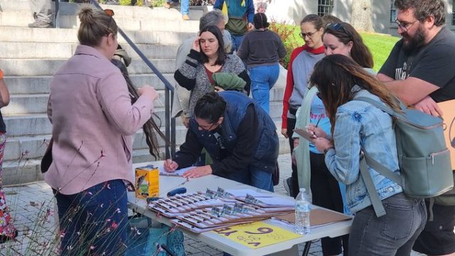 Volunteers were eager to sign up for canvassing shifts to talk to voters about voting Yes on Question 6 on November 7. Photo: Rob Laraway Group of people around a table with forms to sign up for canvassing for Question 6